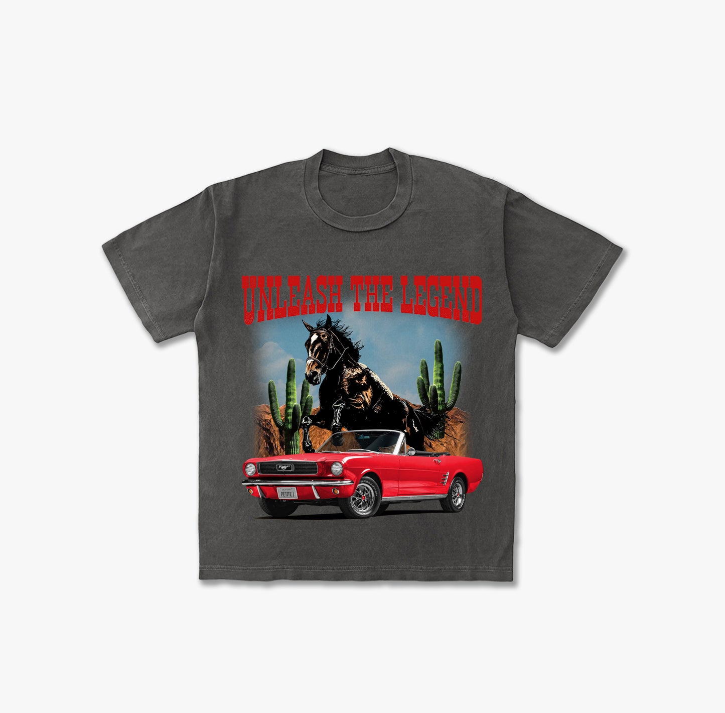 Washed grey t-shirt featuring a red vintage Ford Mustang convertible, a wild black horse rearing, desert landscape with cacti, and red text 'UNLEASH THE LEGEND'.
